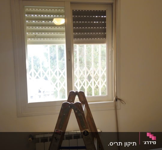 עבודת תיקון תריס גלילה ידני לצד חלון אלומיניום וסולם עבודה